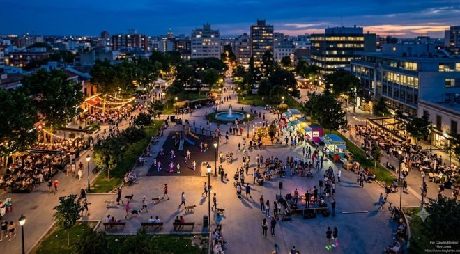 Gente paseando y disfrutando de parques y terrazas en la ciudad durante el anochecer fresco de verano.