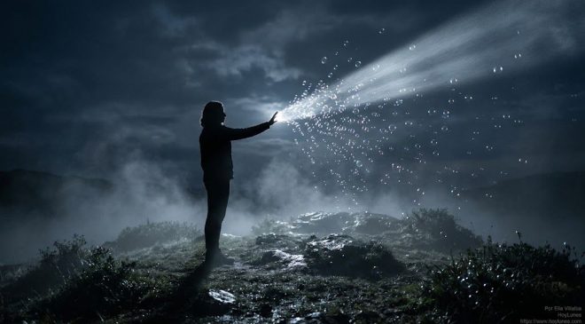Una figura humana de perfil sobre la cima de una colina nocturna rodeada de niebla baja. La persona extiende la mano intentando atrapar un haz de luz de luna denso y plateado que atraviesa la oscuridad. En el punto exacto donde la mano toca la luz, esta se fragmenta en diminutas burbujas de jabón luminosas y efímeras que se disuelven en el aire.